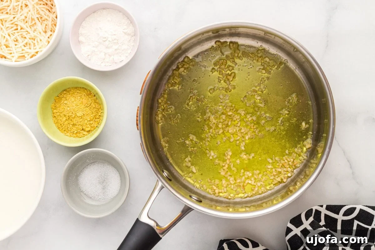 Velvety Plant-Based Alfredo 7 Minced garlic being sautéed in olive oil in a saucepan over low-medium heat.