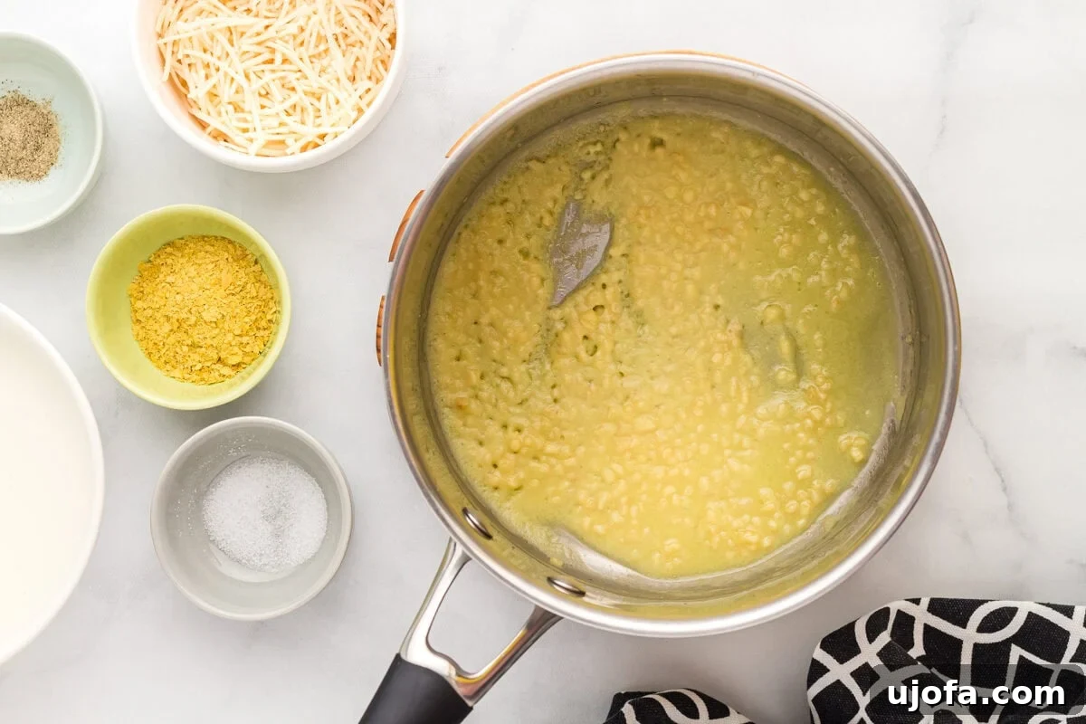 Velvety Plant-Based Alfredo 8 Gluten-free all-purpose flour being whisked into sautéed garlic and oil, forming a roux.
