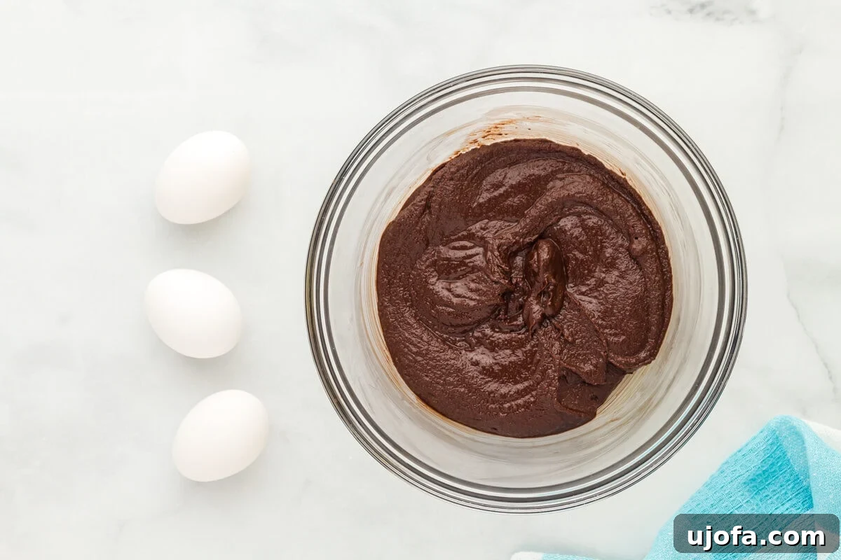 Fudgy Flourless Delights 7 Sugar added to melted chocolate in a glass mixing bowl.