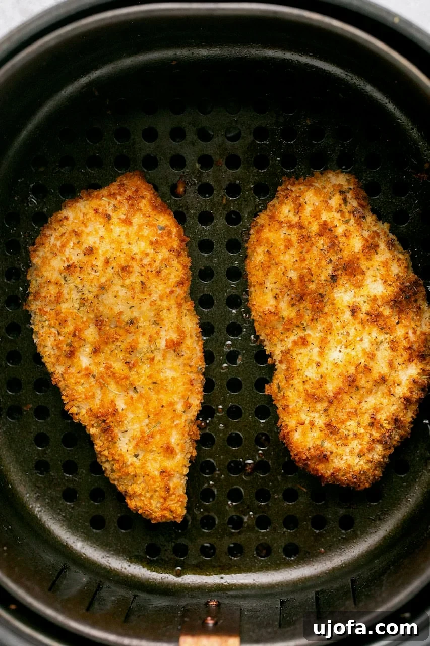 Close-up of crispy, golden-brown chicken cutlets cooking in an air fryer basket, showing the perfect texture achieved.