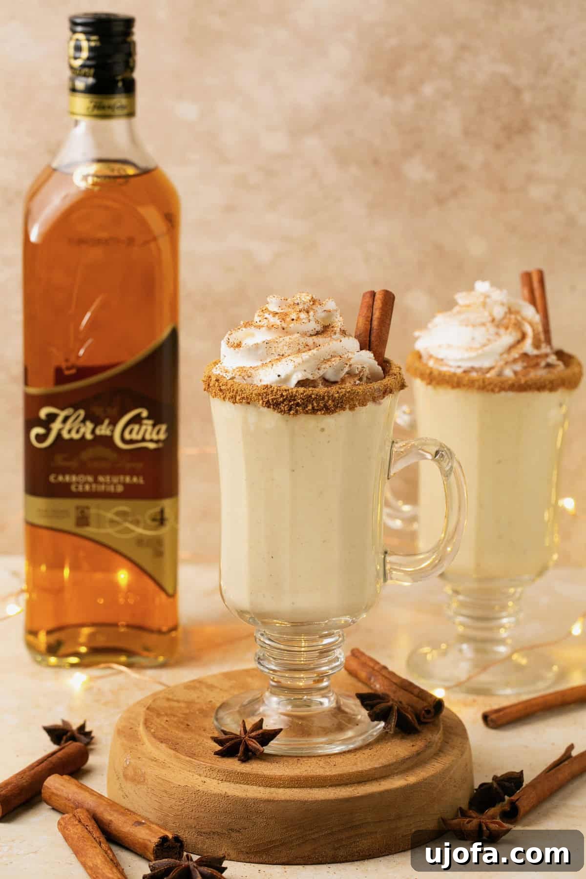 Plant-Based Eggnog 11 A cozy scene featuring a glass of dairy-free eggnog with a bottle of Flor de Caña rum in the soft-focused background, ready for enjoyment.