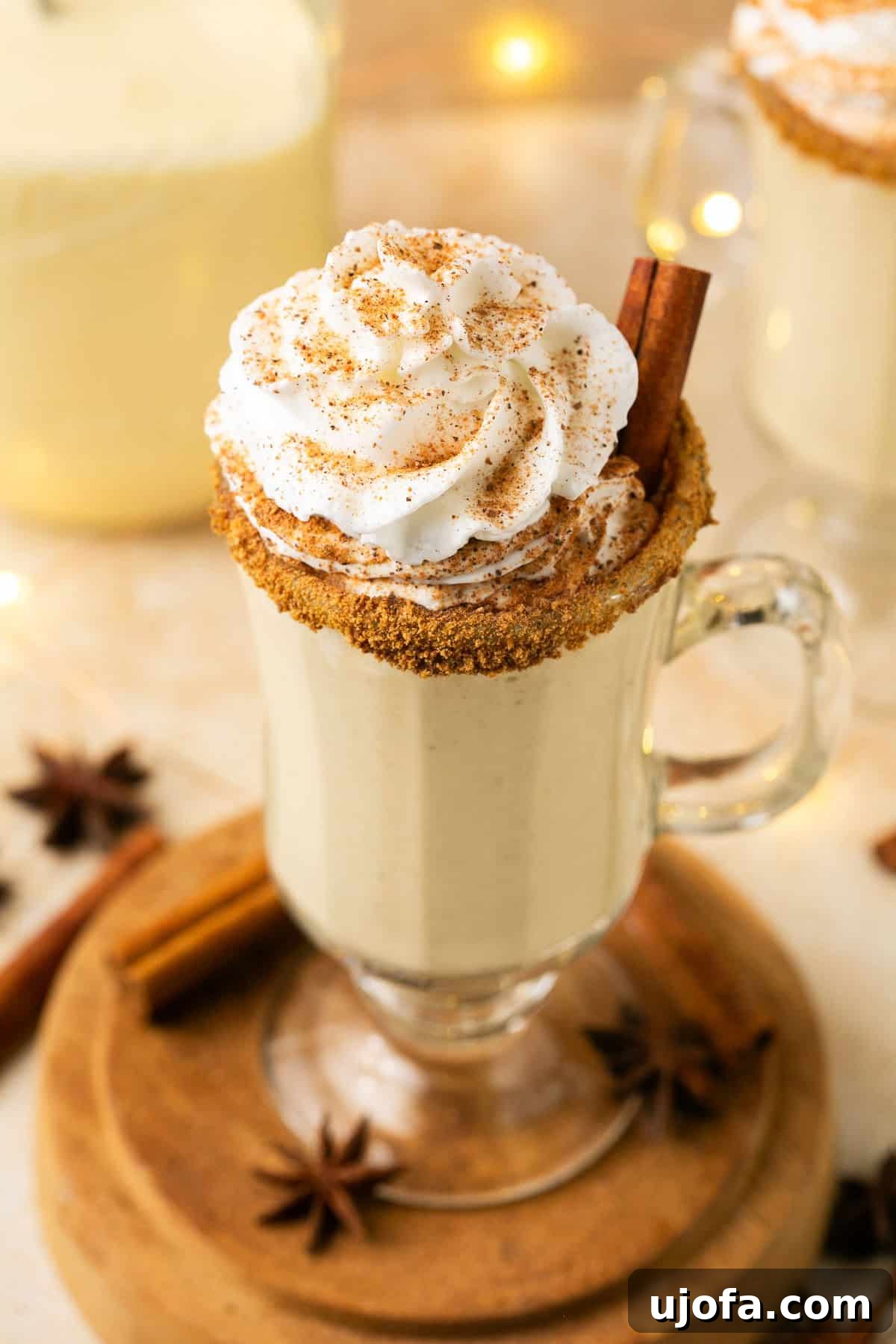 Plant-Based Eggnog 12 A beautifully garnished glass of dairy-free eggnog topped with fluffy whipped cream and a sprinkle of nutmeg, ready to be enjoyed.