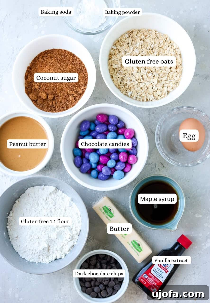 Assorted ingredients for gluten-free monster cookies laid out on a surface, including butter, sugar, peanut butter, oats, and chocolate candies.