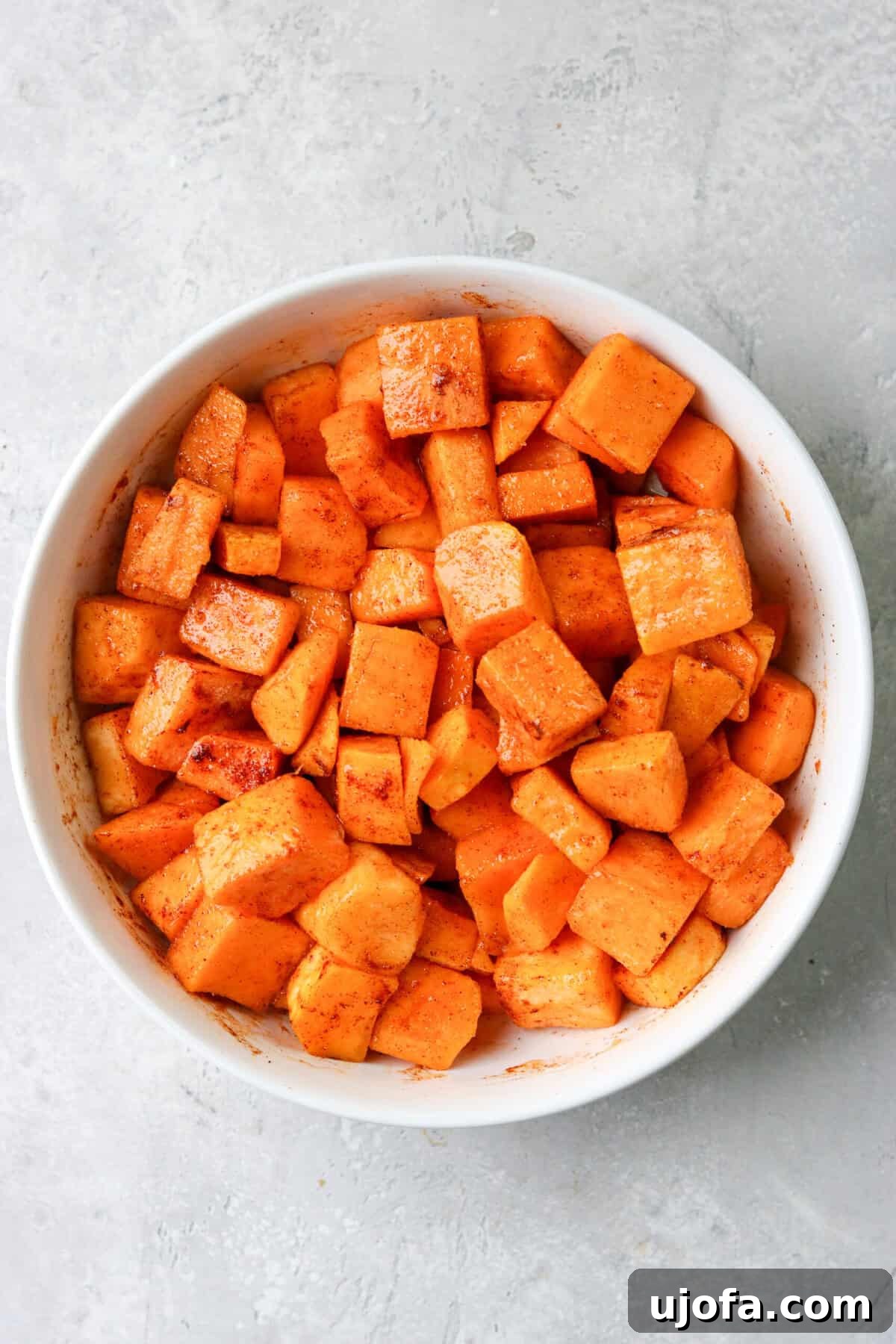 Effortless Air Fryer & Roasted Butternut Squash 4 Butternut squash cubes mixed with oil and seasonings in a white bowl