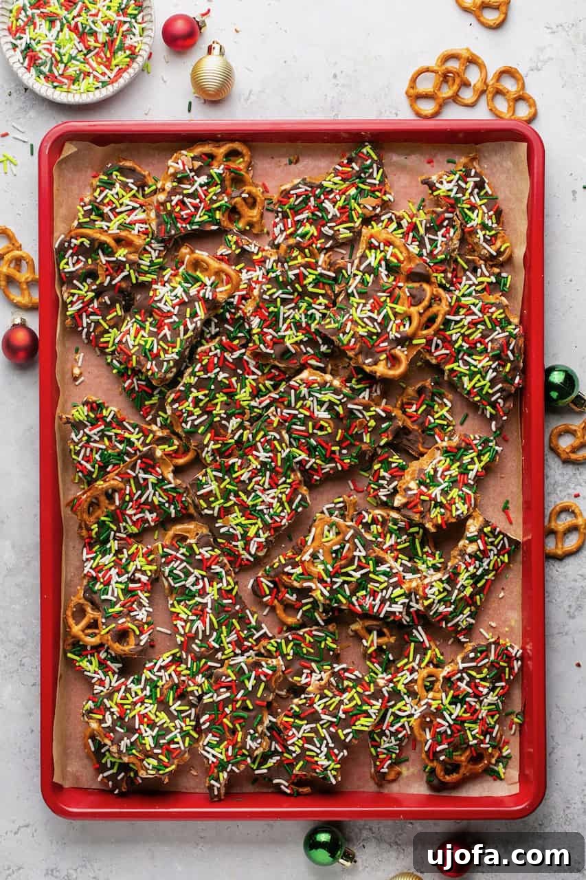 Gluten-free Pretzel Christmas Crack spread out on a red baking sheet, showing individual pieces
