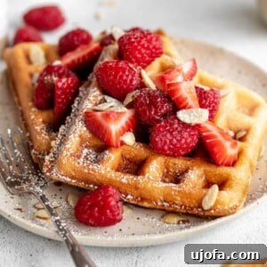 Almond Cloud Waffles 6 Almond flour pancakes with strawberries and almond flakes on top.