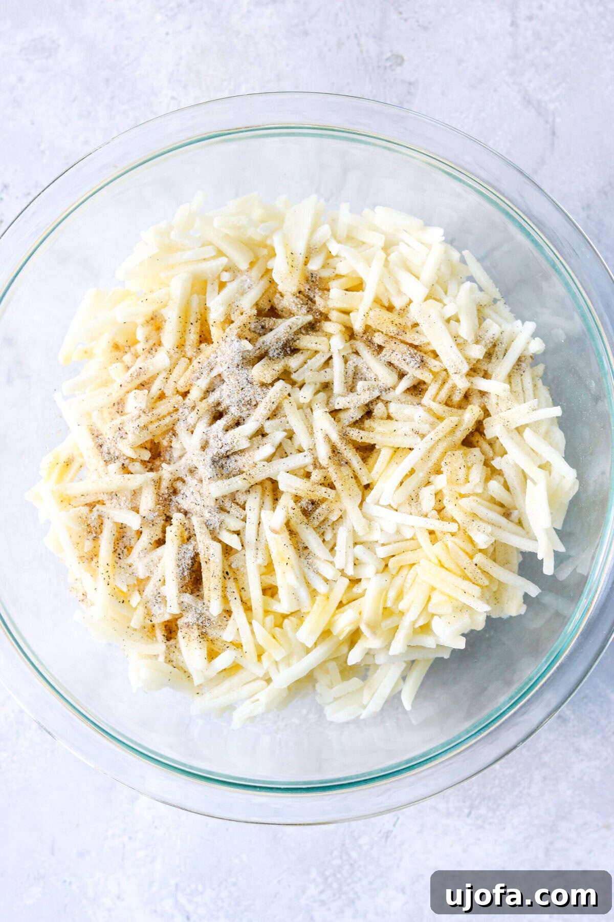 frozen hash browns in a bowl with oil and spices, ready to be cooked