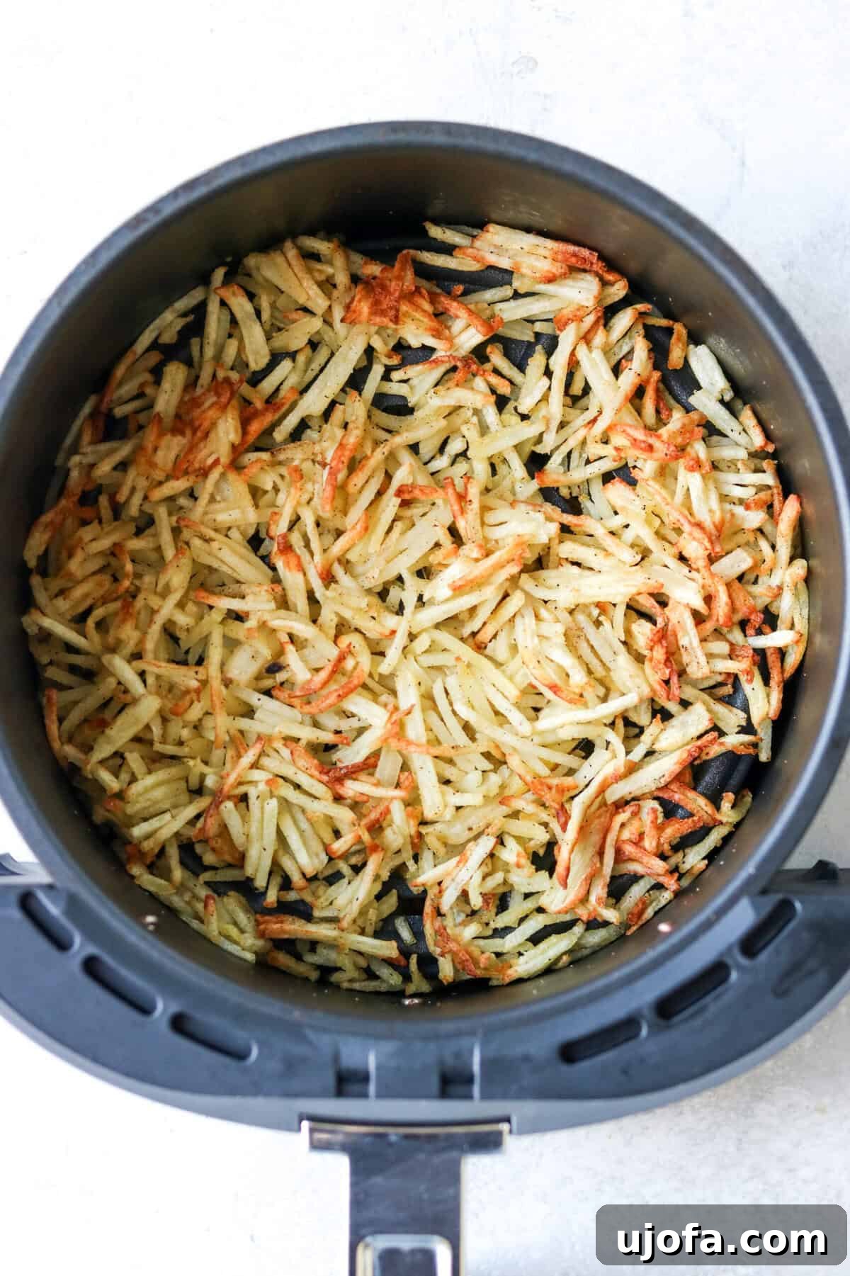 air fryer frozen hash browns cooked to perfection in an air fryer basket