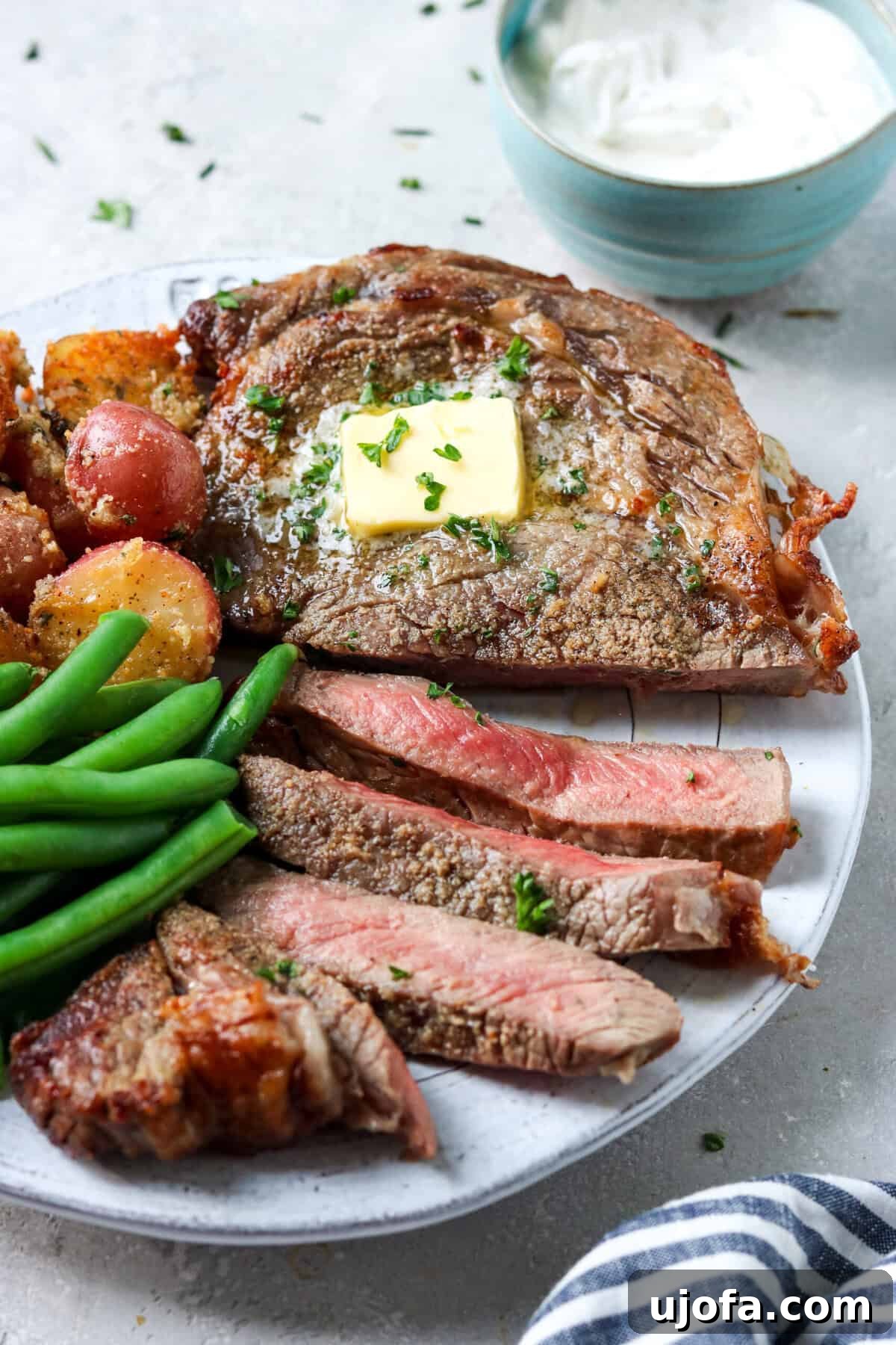 A stunning ribeye steak plated with a side of vibrant green beans and wholesome roasted potatoes, showcasing a complete and inviting meal.