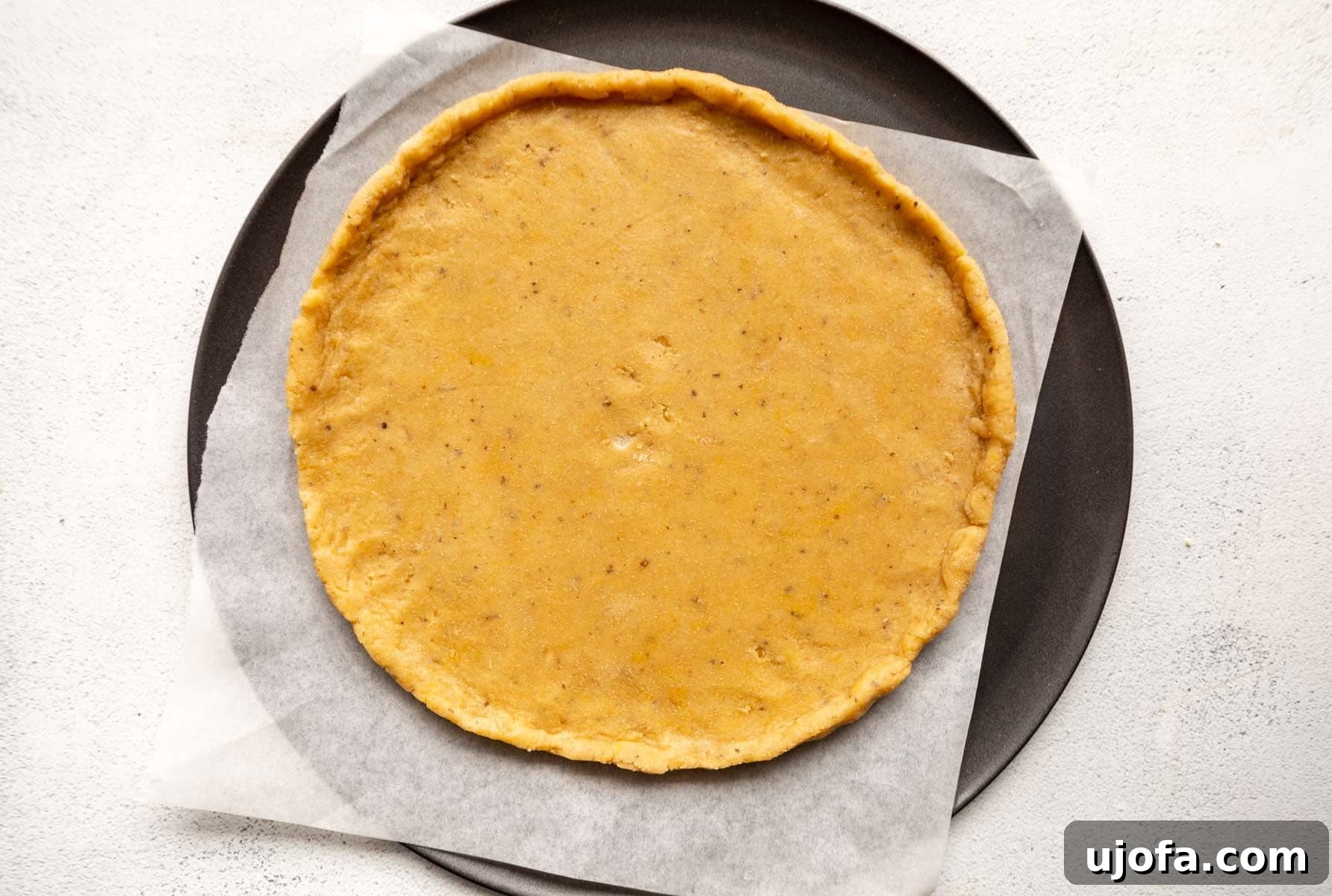 Crispy Gluten-Free Almond Flour Pizza Crust 10 Almond flour pizza dough rolled into a perfect circle on a parchment-lined pizza pan, with a small lip around the edge.