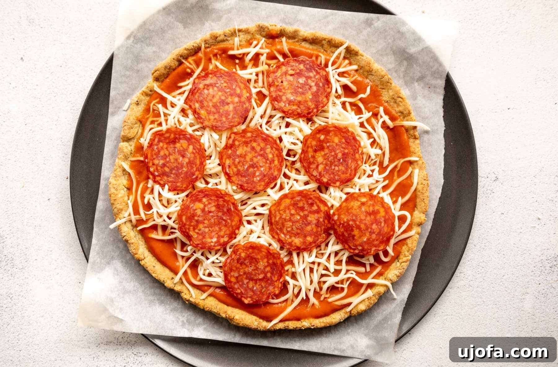 Crispy Gluten-Free Almond Flour Pizza Crust 12 An almond flour pizza crust generously topped with marinara sauce, melted cheese, and pepperoni slices, ready for its final bake.