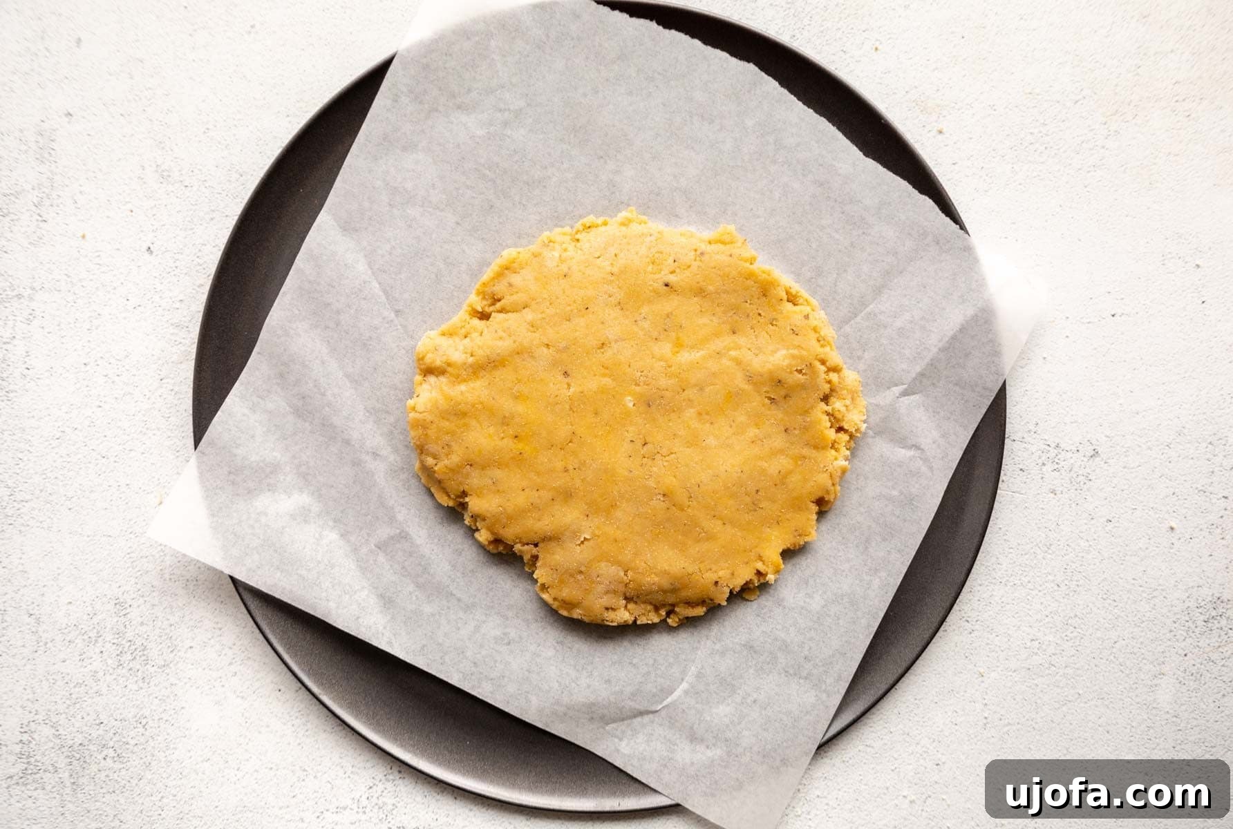 Crispy Gluten-Free Almond Flour Pizza Crust 9 Almond flour pizza dough formed into a ball and placed on a parchment-lined pizza pan, ready for rolling.