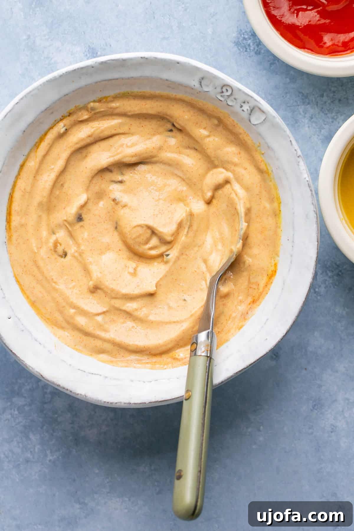 big mac sauce in a bowl with a spoon with ketchup and mustard on the side