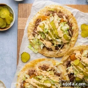smash burger big mac tacos on parchment paper topped with lettuce pickles and sauce