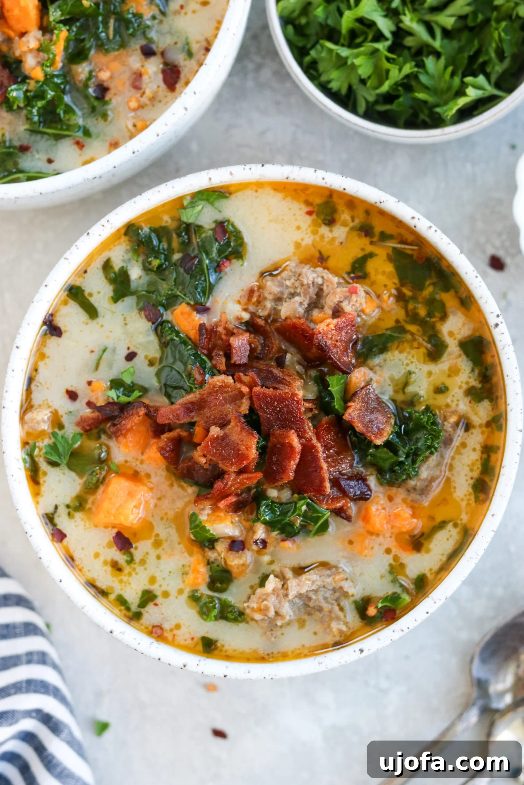 Whole30 Paleo Zuppa Toscana 2 A steaming bowl of Whole30 Zuppa Toscana, garnished with crispy bacon crumbles and fresh parsley.