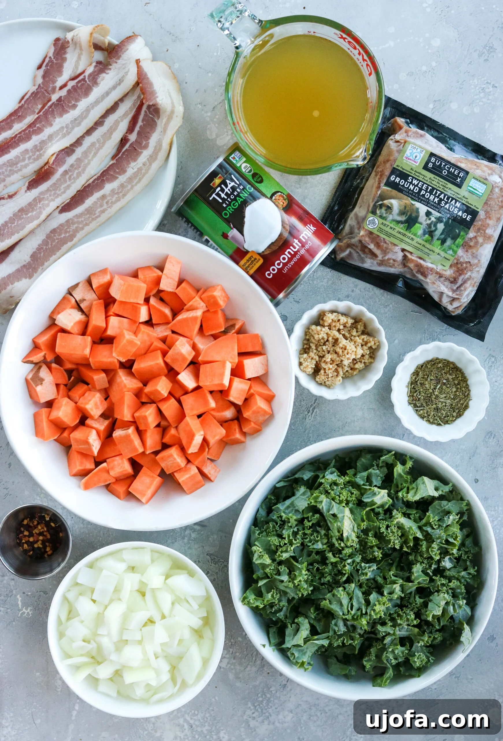 Whole30 Paleo Zuppa Toscana 3 A selection of fresh ingredients for Whole30 Zuppa Toscana, neatly arranged in small bowls, including sausage, kale, sweet potatoes, and spices.