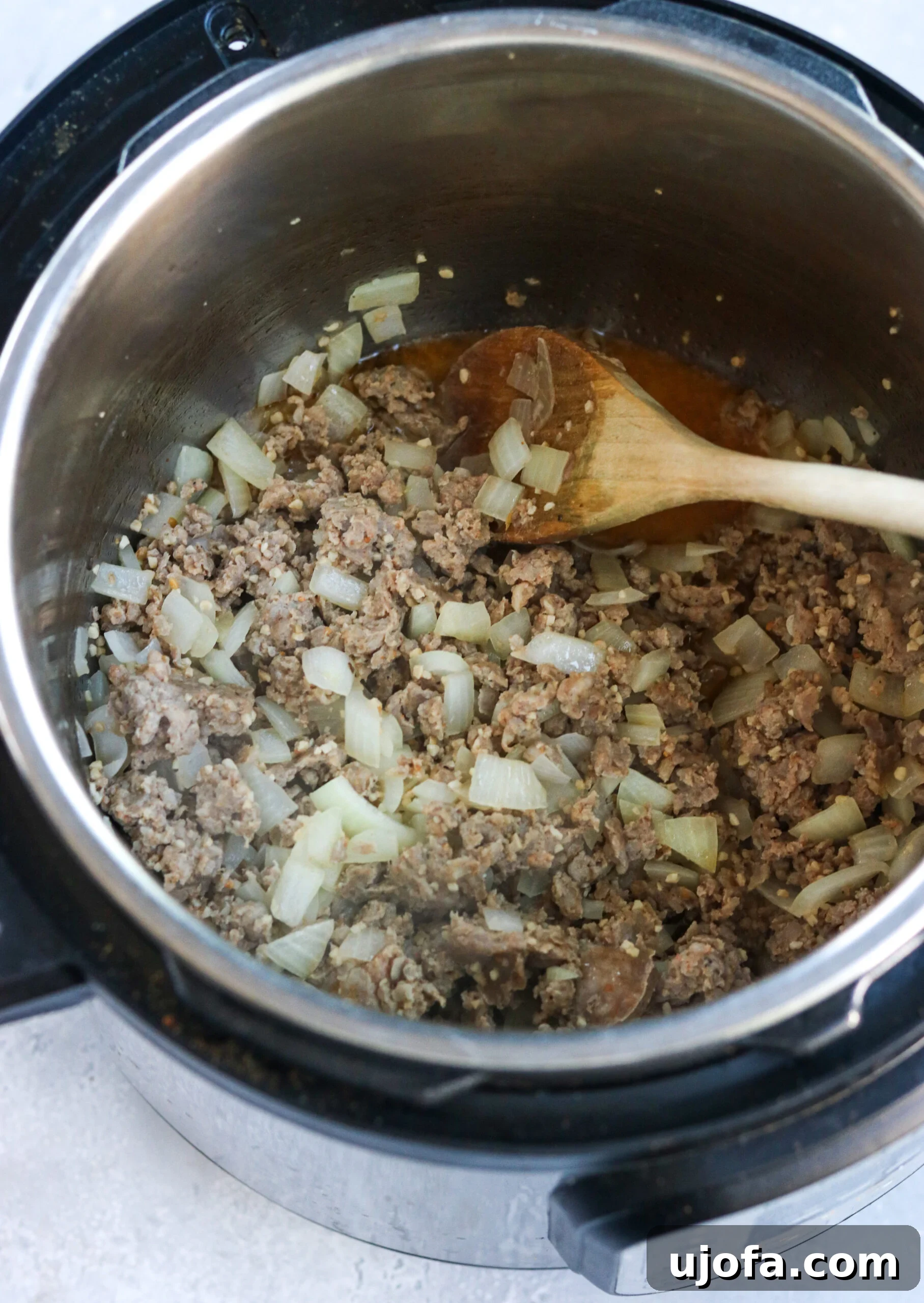 Whole30 Paleo Zuppa Toscana 4 Sautéed Italian sausage, onions, and garlic cooking together in an Instant Pot, forming the base of the Zuppa Toscana.