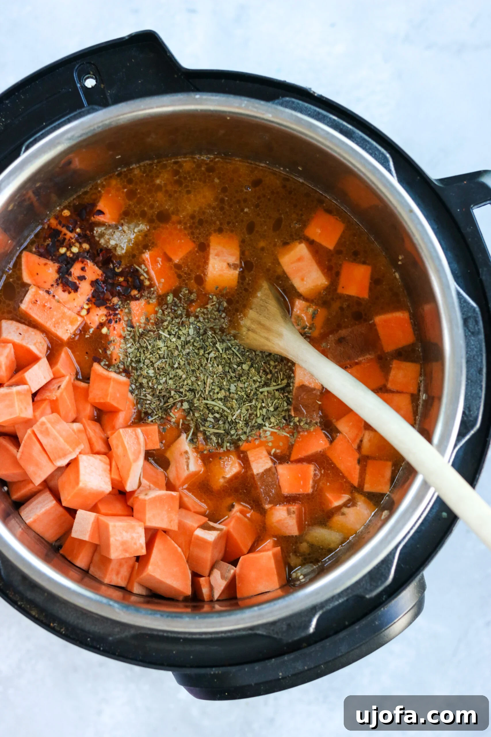 Whole30 Paleo Zuppa Toscana 5 Diced sweet potatoes being added to the Instant Pot, joining the sautéed sausage and aromatics for Zuppa Toscana.