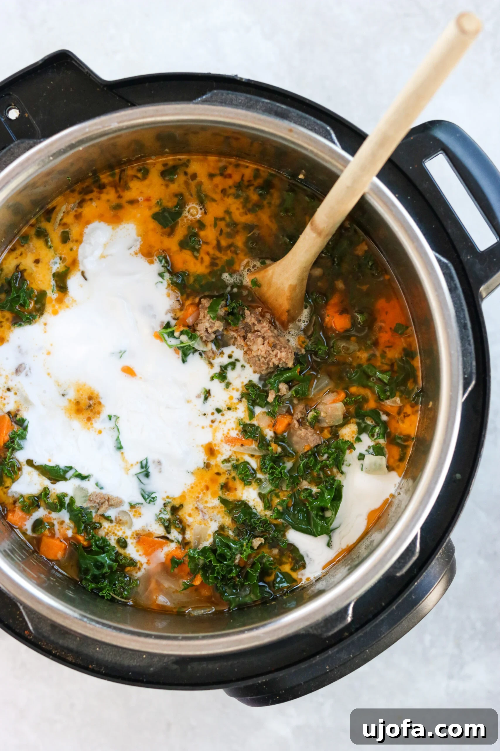 Whole30 Paleo Zuppa Toscana 6 Thick coconut milk being stirred into the Instant Pot Zuppa Toscana, creating a rich and creamy broth.