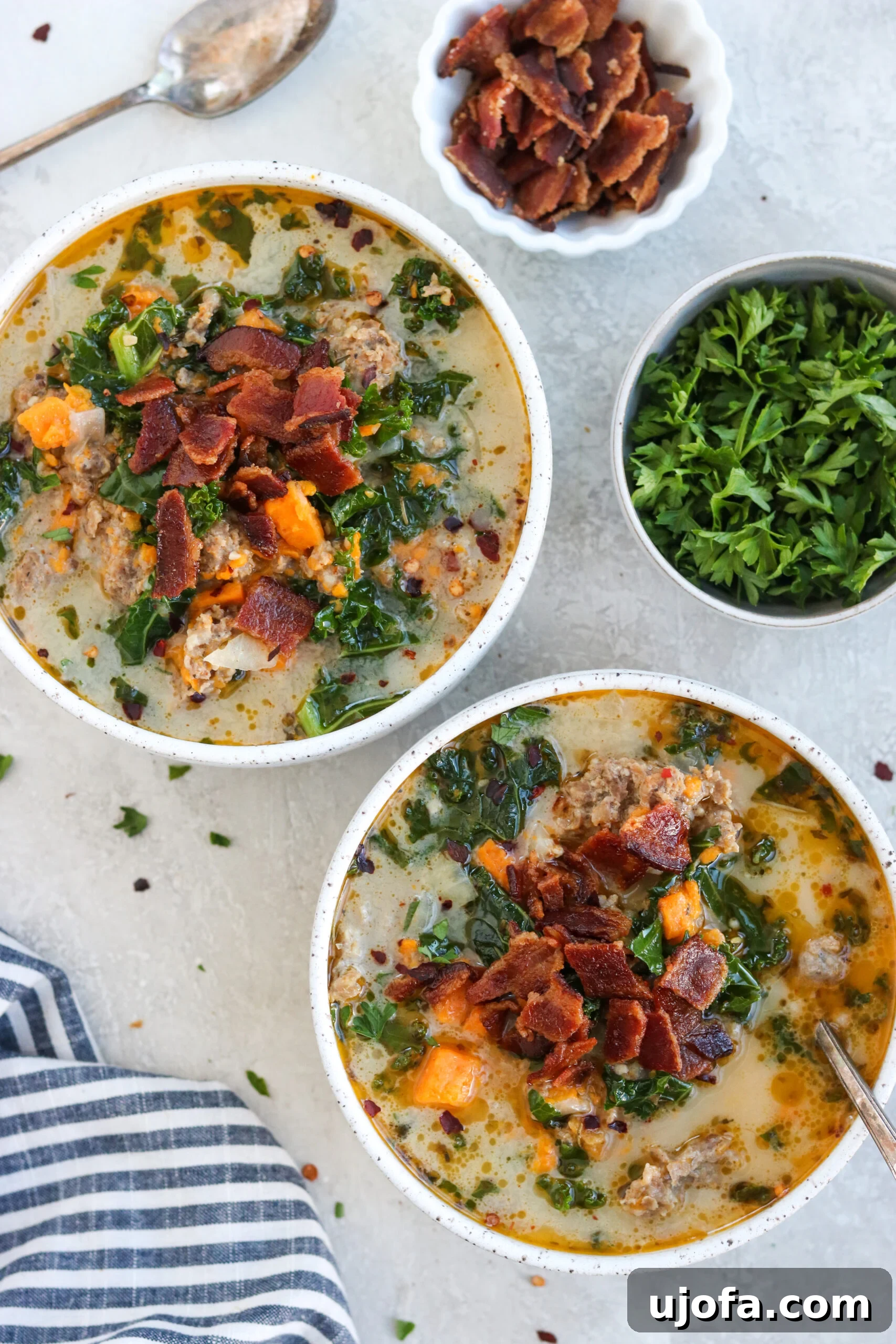 Whole30 Paleo Zuppa Toscana 8 Two white bowls filled with steaming Whole30 Zuppa Toscana, garnished with fresh herbs and ready to be enjoyed.