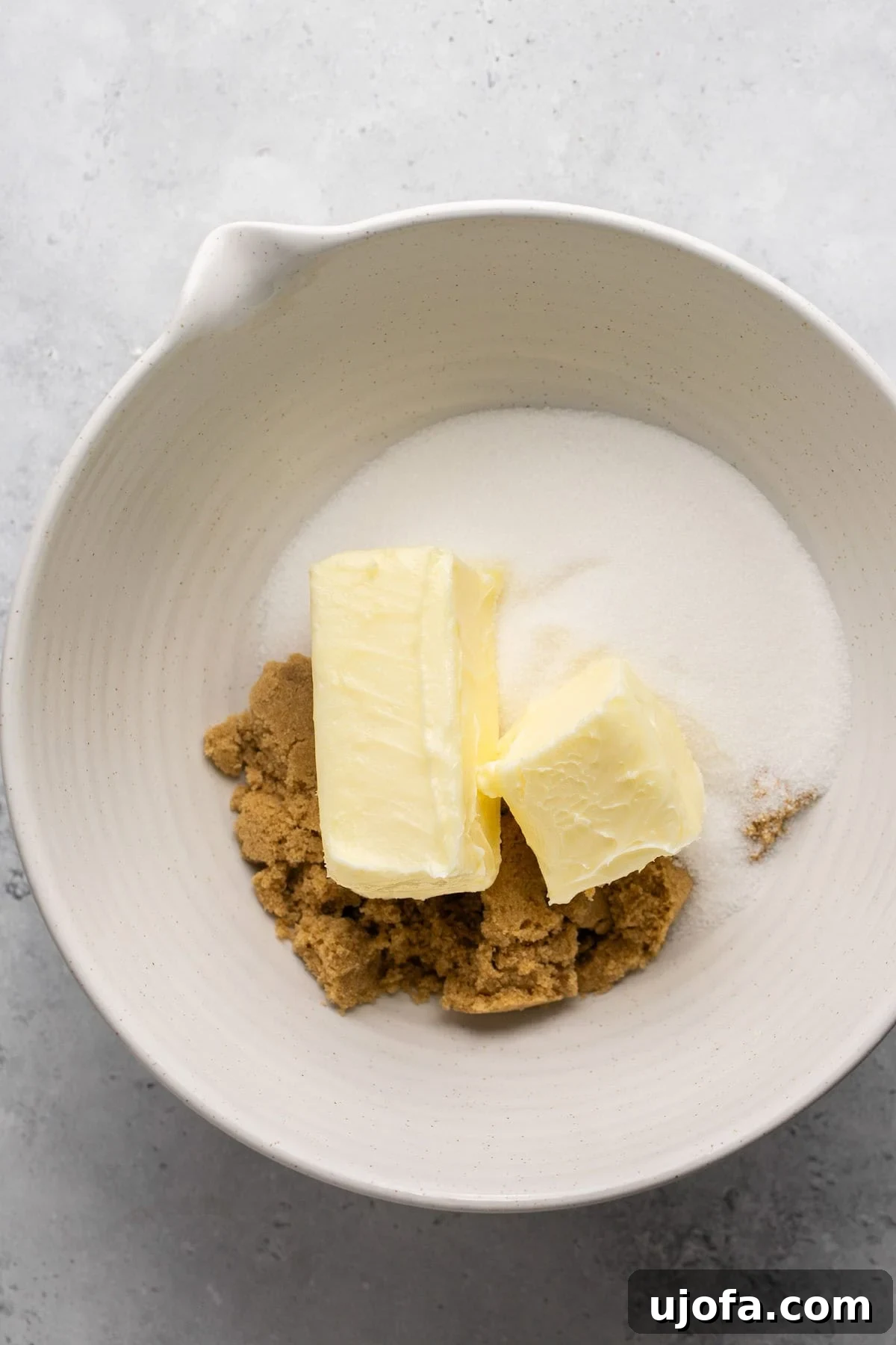 Softened butter, granulated sugar, and light brown sugar in a mixing bowl, ready to be creamed.