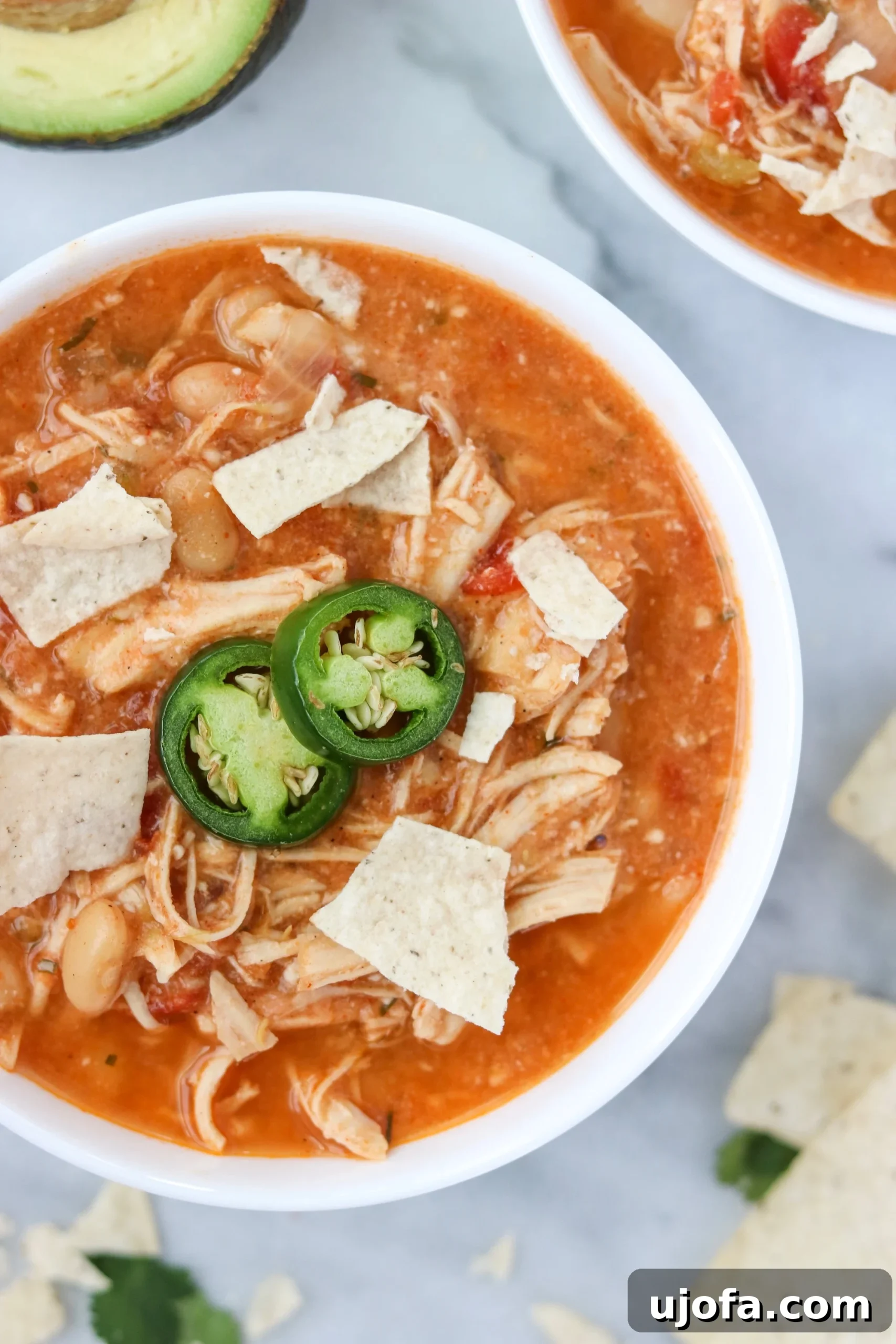 Close-up shot of tender shredded chicken in a slow cooker, simmering in a rich, creamy chili base.