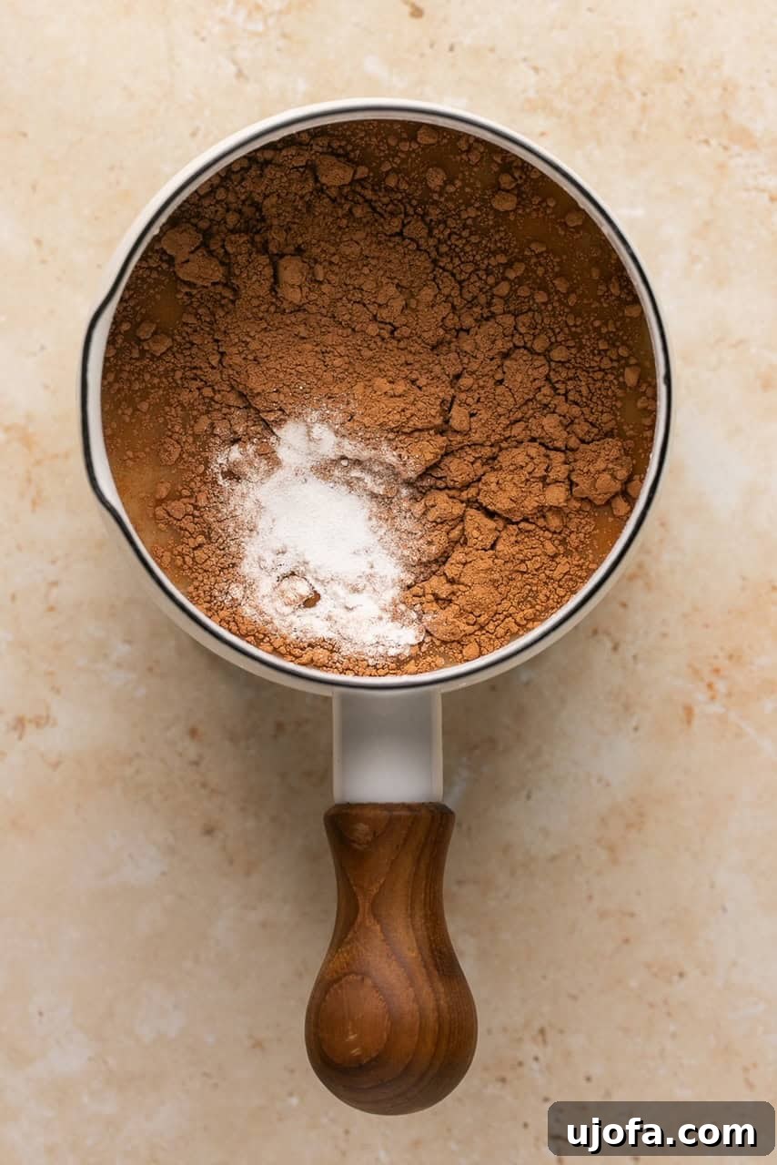 a small sauce pan with collagen, broth, cocoa powder, and maple syrup in it