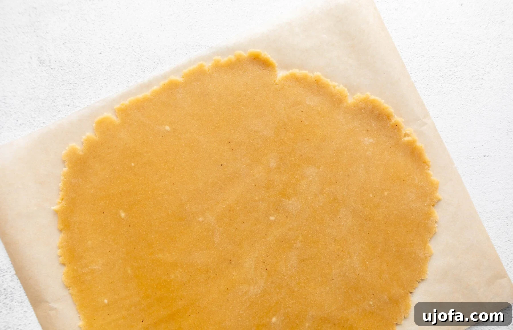 Gluten-Free Almond Flour Pie Crust process shot: rolling out dough between parchment paper.