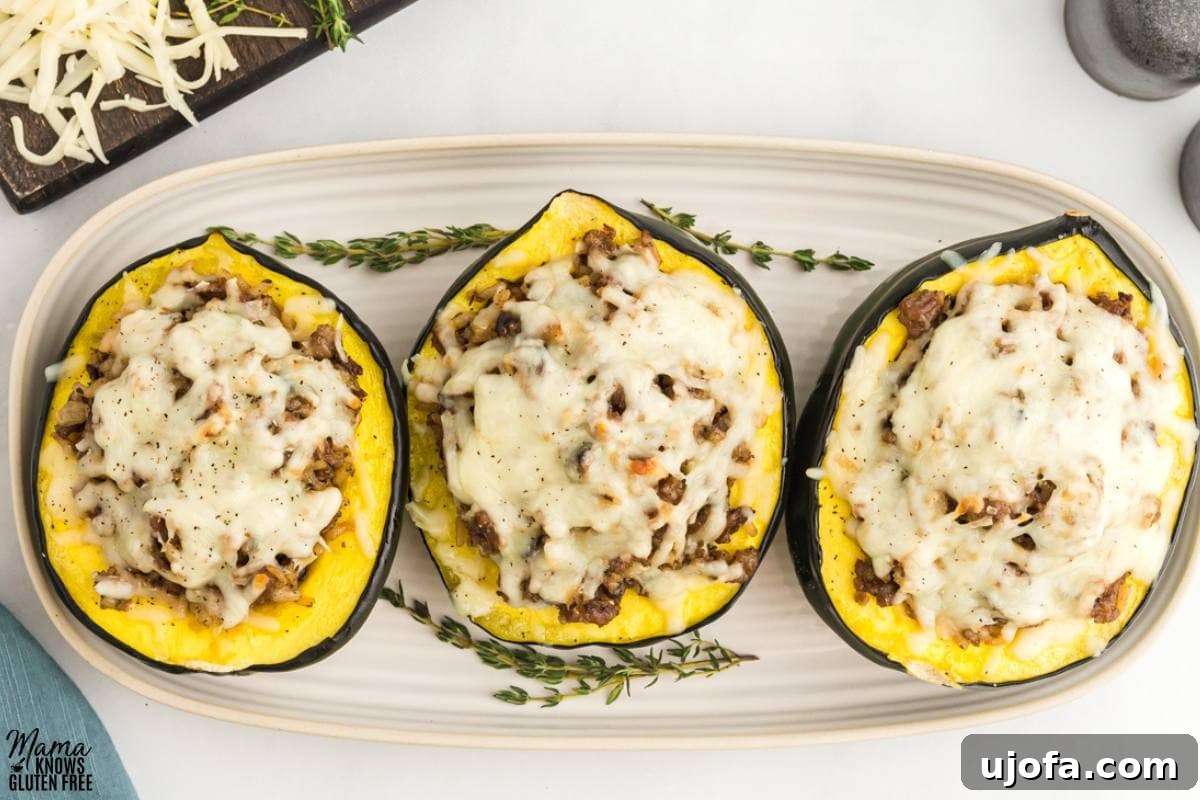 Three beautifully presented gluten-free stuffed acorn squash halves on an oval serving platter, garnished for a festive fall meal.