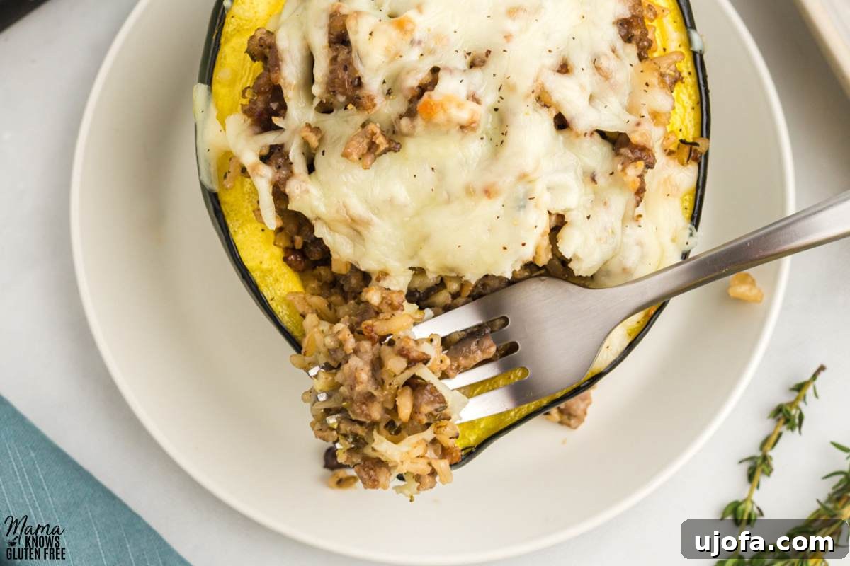 A fork gently scooping the savory stuffing out of a single gluten-free acorn squash half on a white plate, showcasing the rich filling.