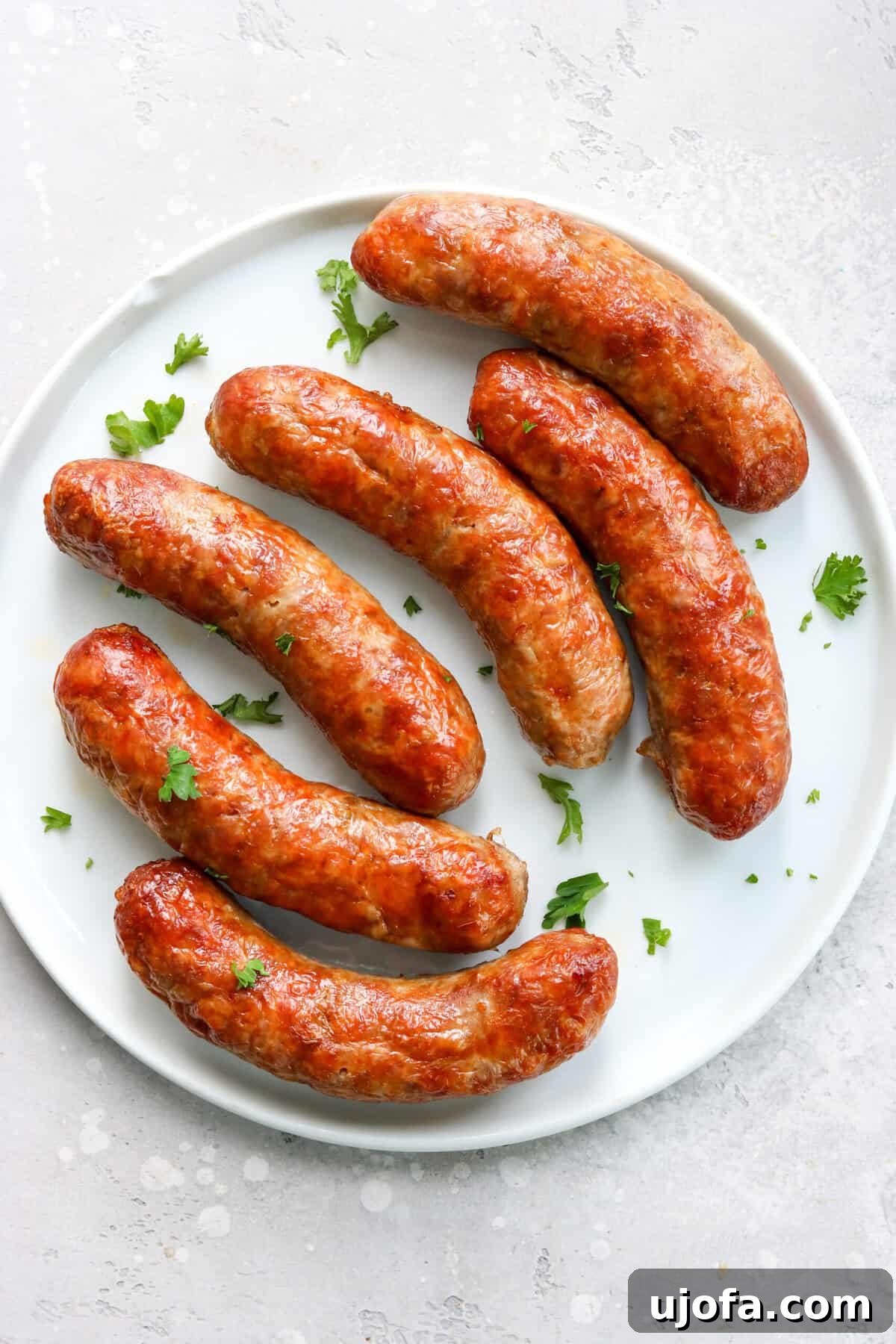 Quick and Crispy Air Fryer Italian Sausage 2 Crispy, golden-brown air-fried Italian sausage on a white plate, garnished with fresh parsley.