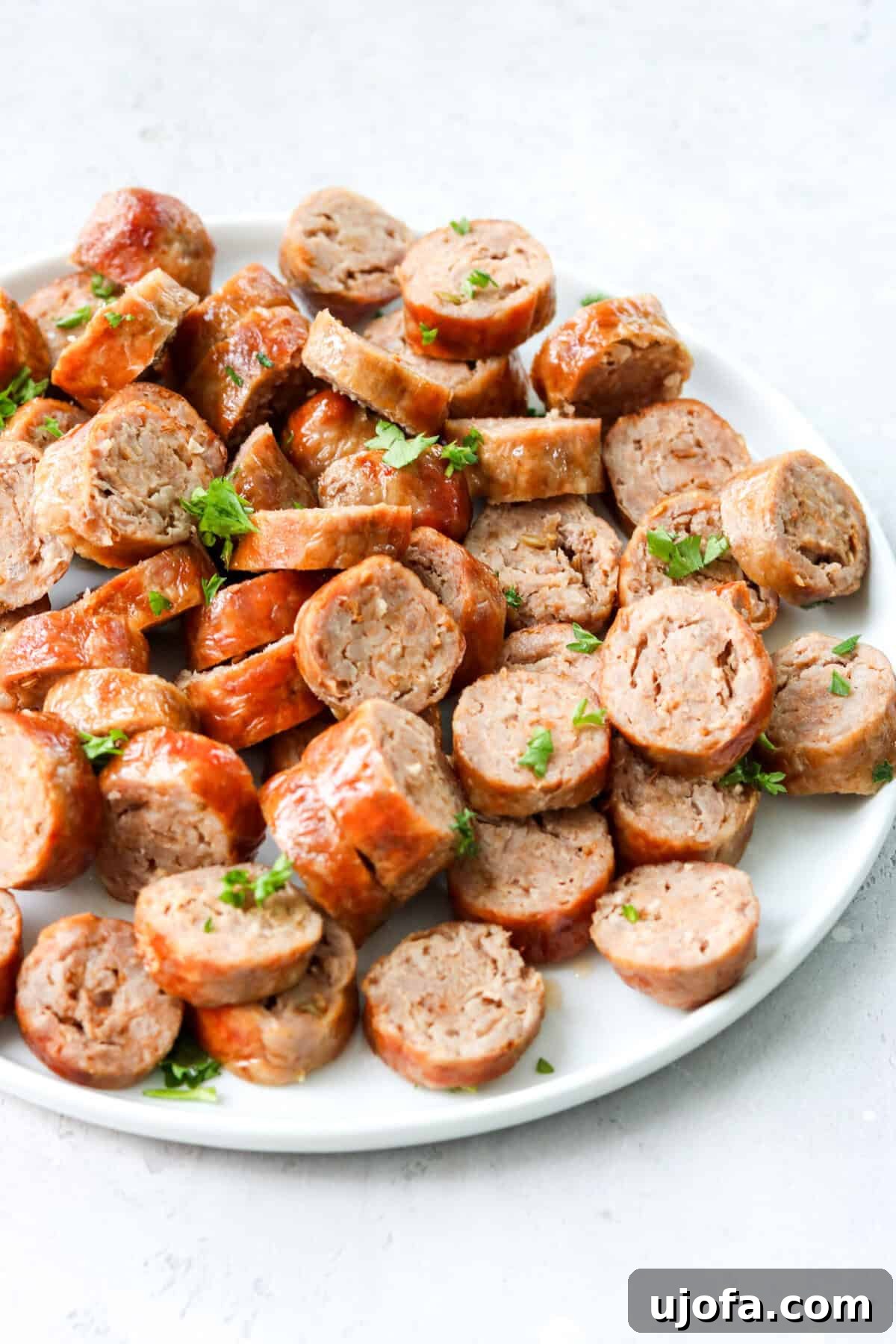 Quick and Crispy Air Fryer Italian Sausage 6 Slices of perfectly cooked Italian sausage on a white plate, topped with fresh green parsley, ready to be served.