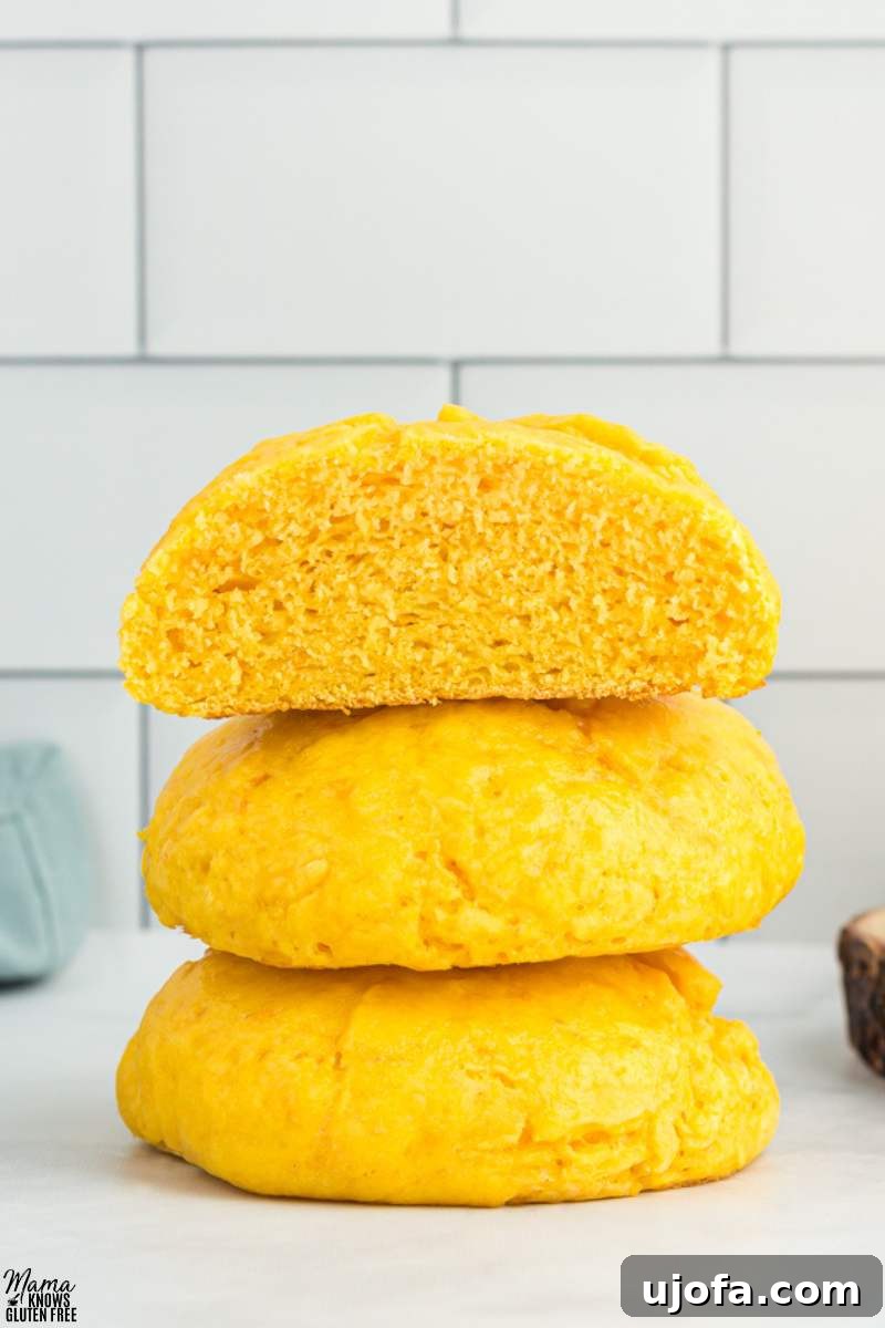 Three Gluten-Free Sweet Potato Rolls  piled on top of each other with top one cut open to show interior.