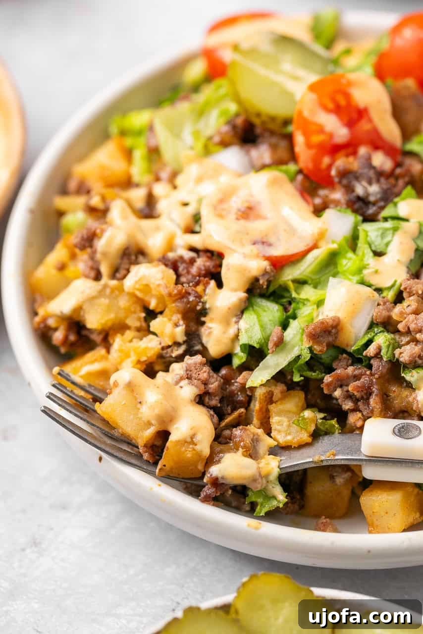 A close-up shot of Big Mac Casserole, highlighting the rich ground beef and potato base, drizzled with special sauce and topped with fresh lettuce and cherry tomatoes, ready to be enjoyed.