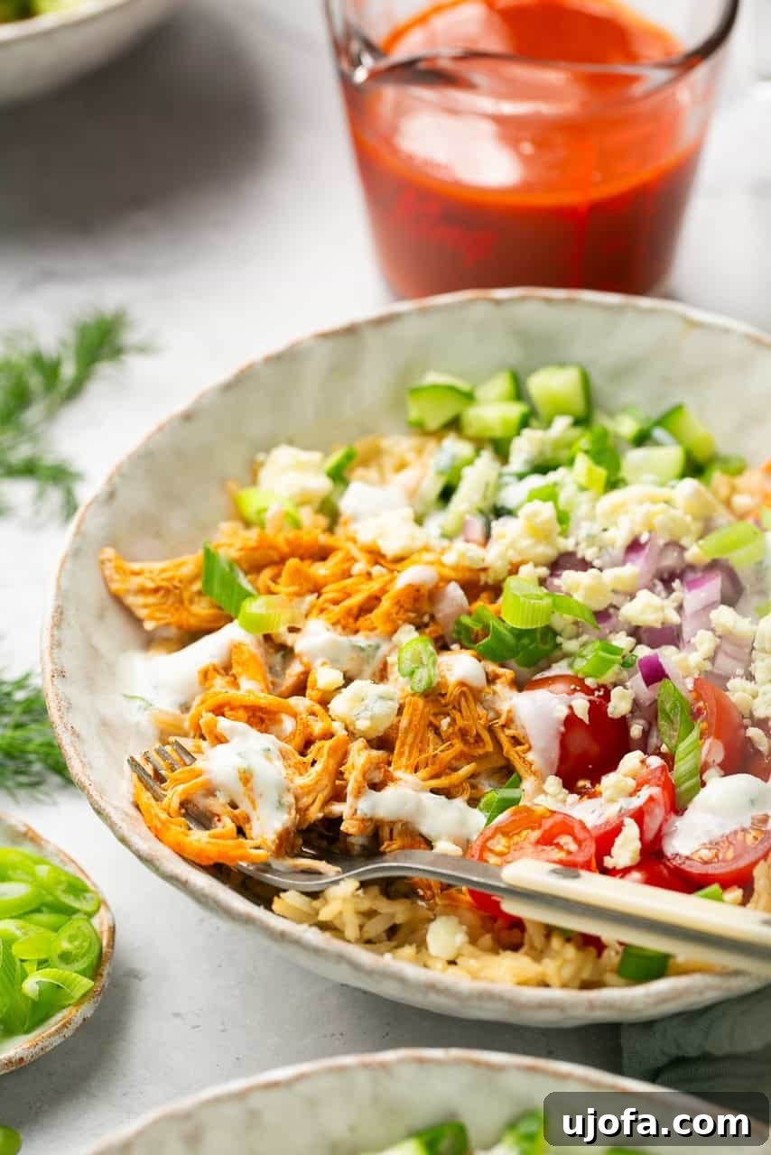 a side view of slow cooker buffalo chicken and rice bowls with tomatoes and cucumbers 