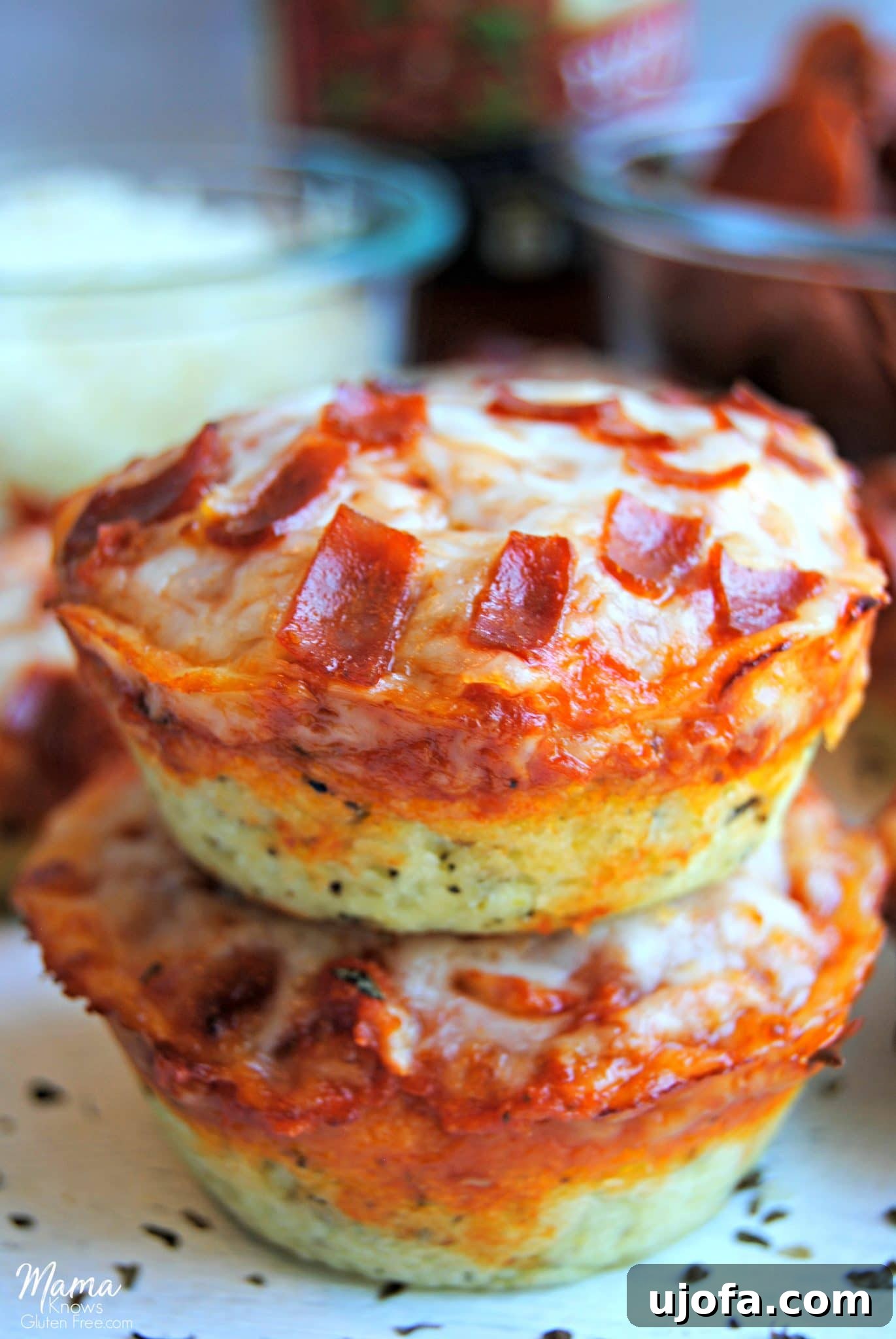 Gluten-Free Pizza Bites Dairy-Free Friendly 2 Two golden-brown gluten-free deep dish pizza bites, perfectly stacked, with a vibrant array of pizza toppings blurred in the background, hinting at endless customization possibilities.