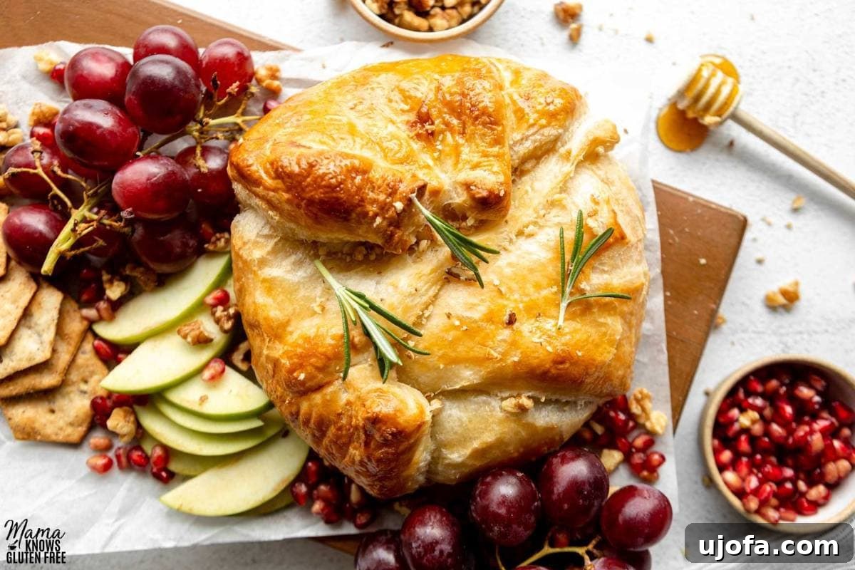 Gluten-Free Baked Brie surrounded by grapes, sliced apples, pomegranate seeds and crackers.