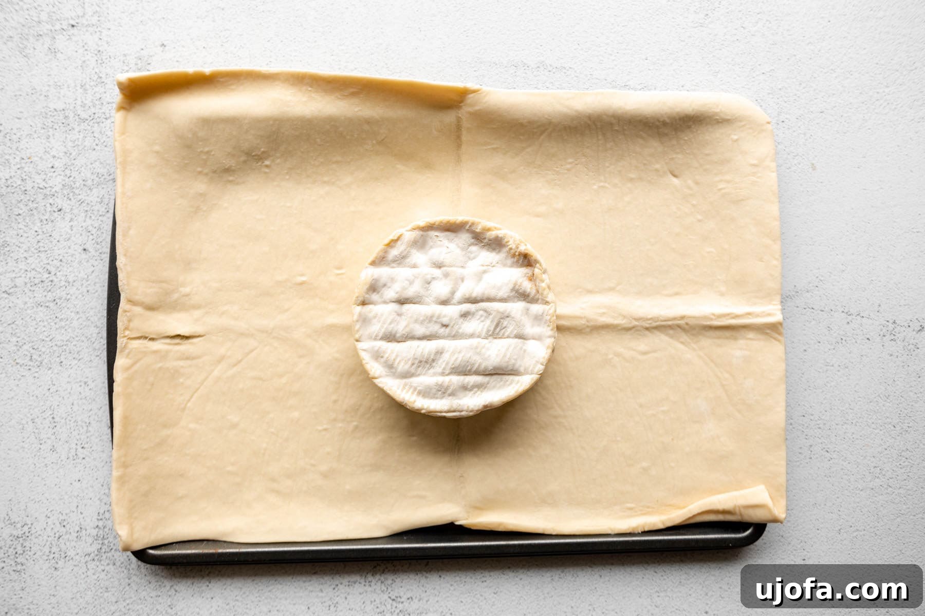 A wheel of brie on a gluten-free puff pastry sheet.