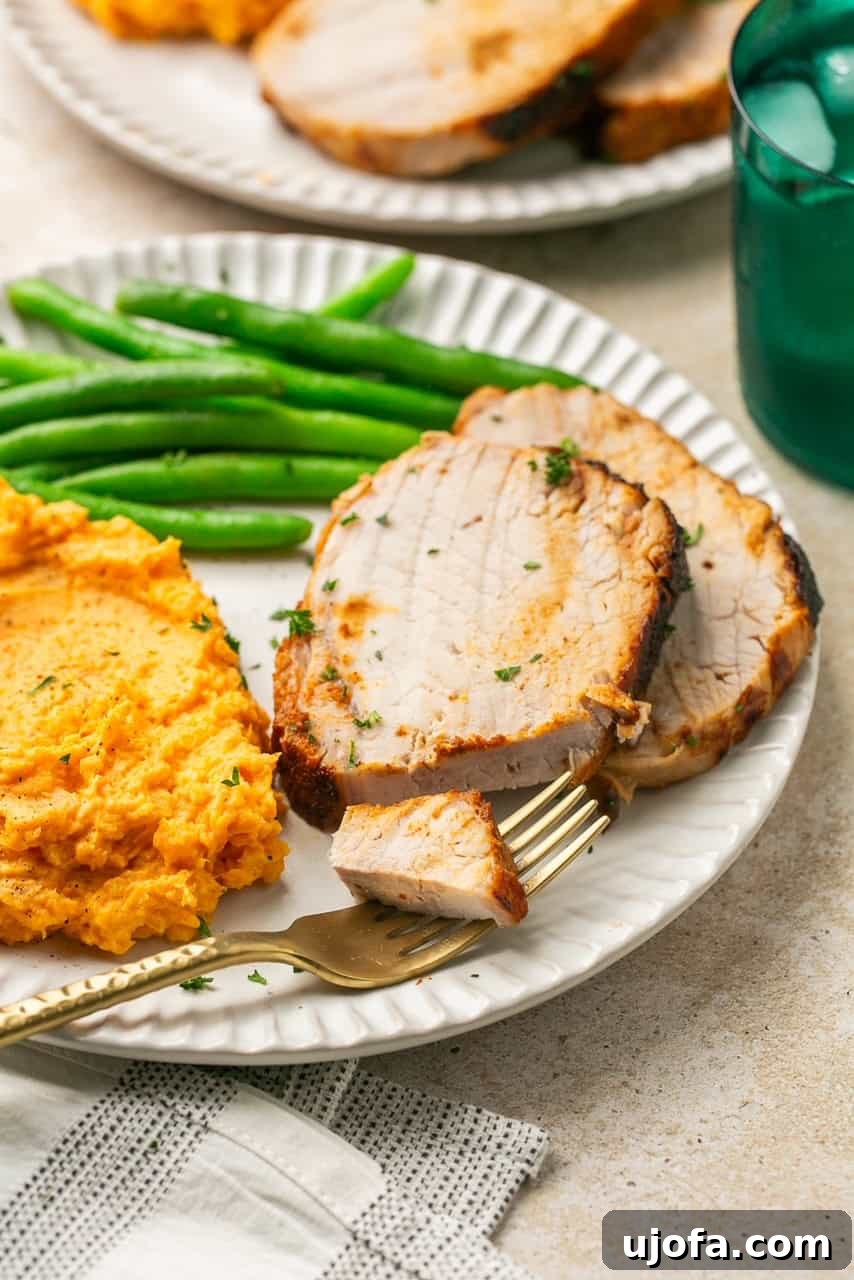 Golden Crust Air Fryer Pork Roast 7 2 slices of pork roast on a plate with mashed sweet potatoes and green beans