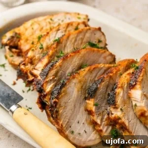 air fryer pork roast sliced on a white platter with a knife