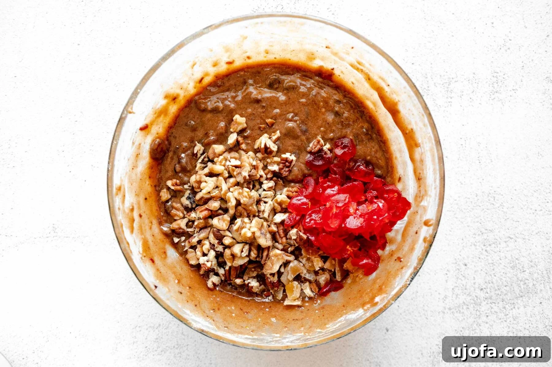 Sumptuous Gluten-Free Fruitcake 9 Gluten-free fruit cake batter in a glass mixing bowl with candied cherries, walnuts, pecans, and crystallized ginger folded in.