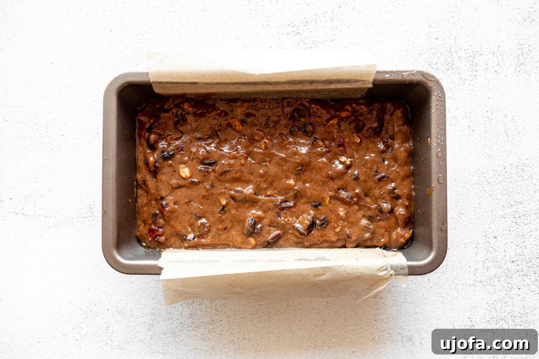Sumptuous Gluten-Free Fruitcake 10 Gluten-free fruit cake batter transferred evenly into a parchment-lined loaf pan, ready for baking.