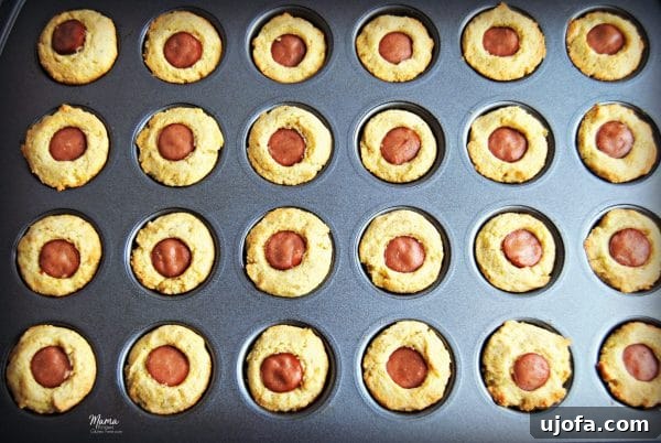 Close-up of golden brown gluten-free mini corn dogs in a muffin pan.
