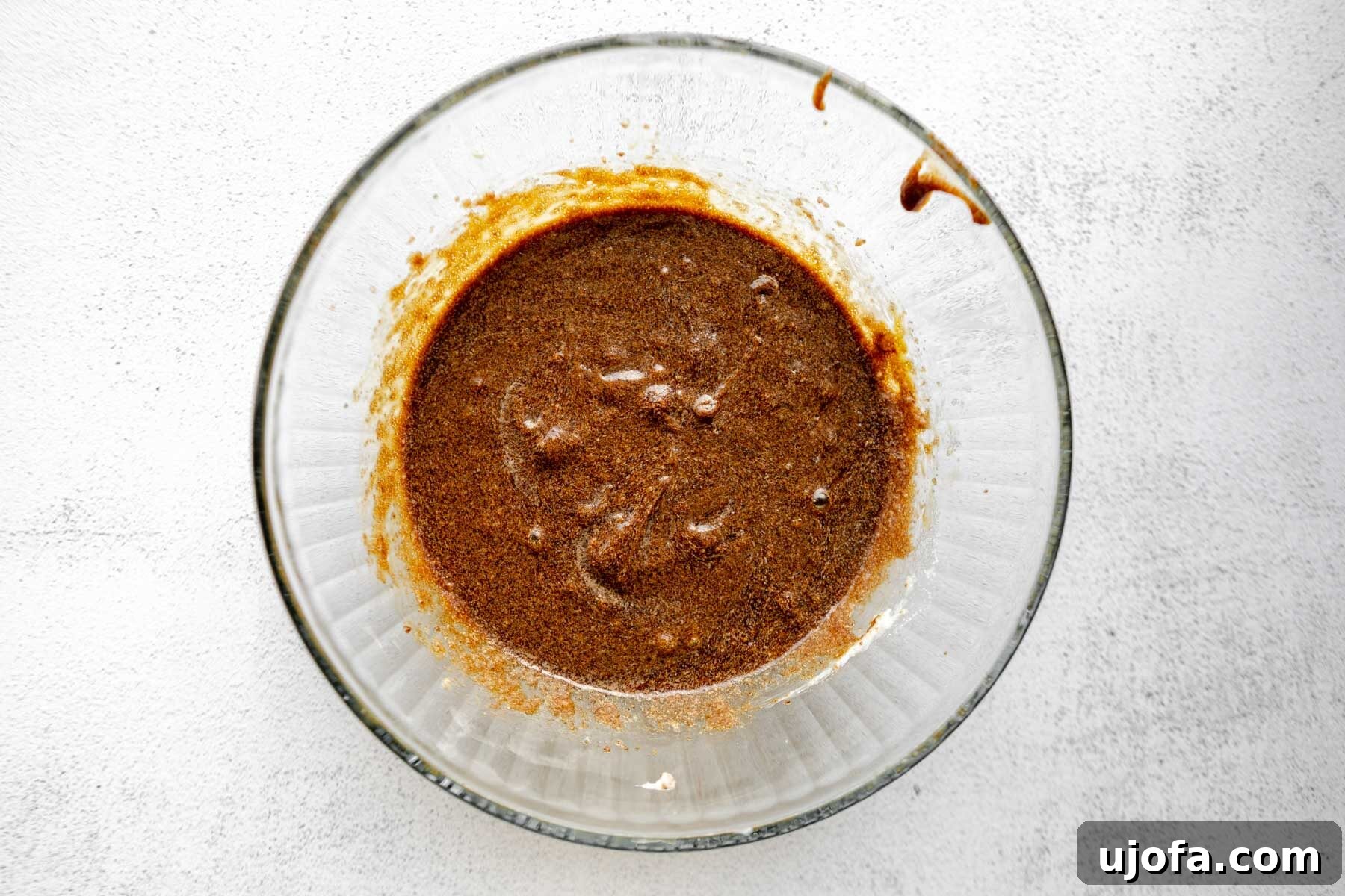 Soft & Chewy Gluten-Free Molasses Spice Cookies 7 The wet ingredients, including butter, sugars, egg, and molasses, being whisked together in a glass mixing bowl, creating a smooth, dark mixture.