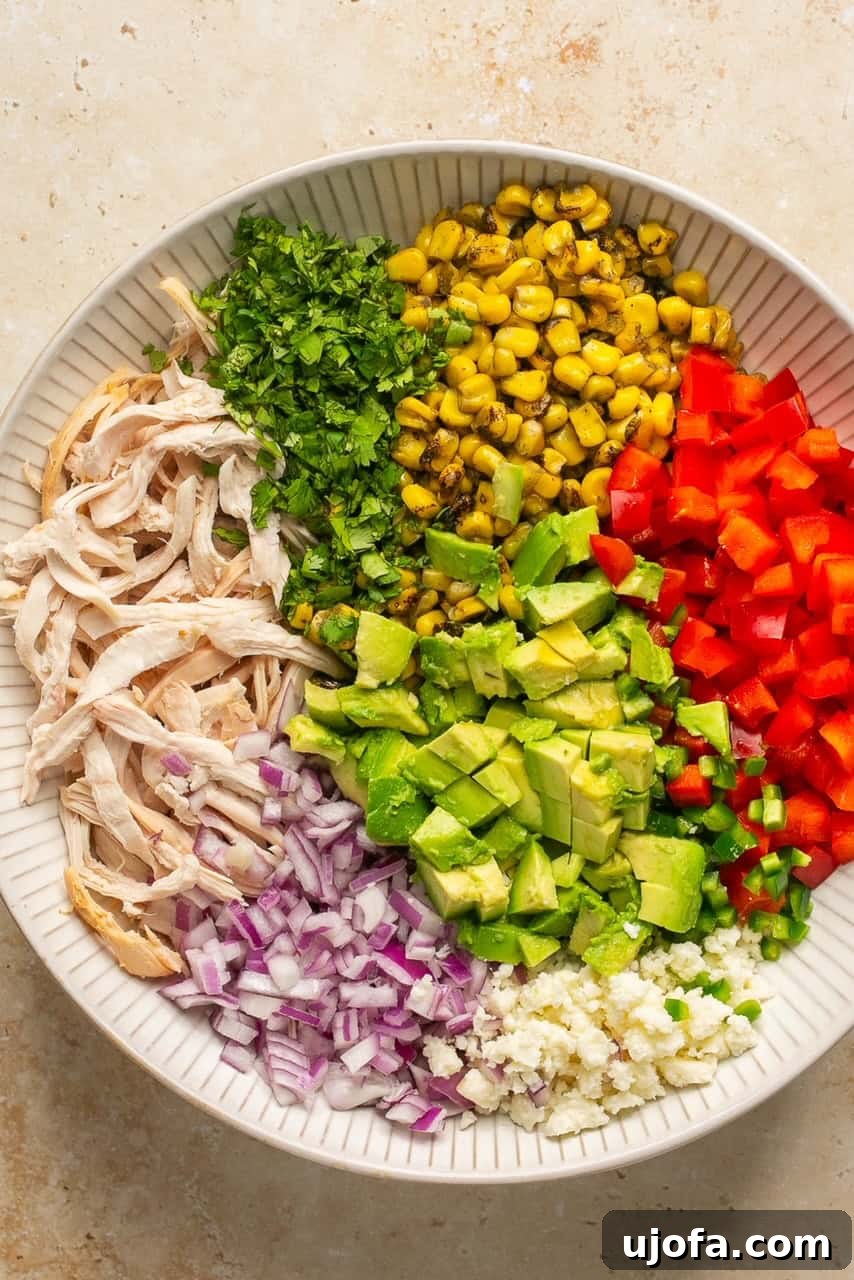 Various salad ingredients including chicken, corn, and bell pepper, combined in a large mixing bowl.