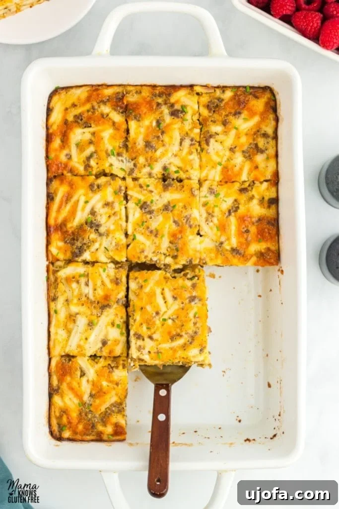 Gluten-free breakfast casserole with sausage, hash browns, eggs, and melted cheese, ready to be sliced.