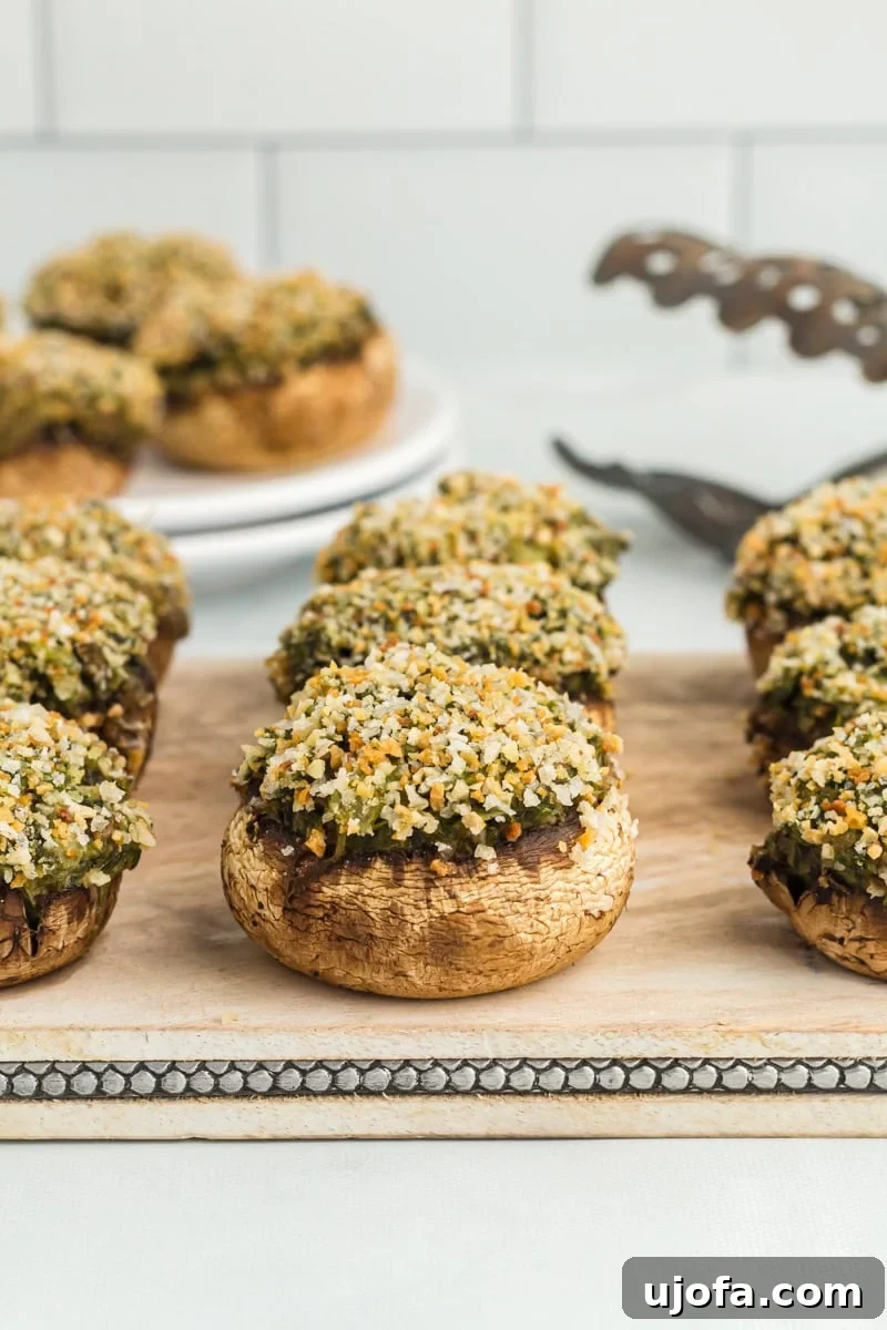 Wholesome Mushroom Poppers 2 Side view of gluten-free stuffed mushrooms on a wooden chopping board.