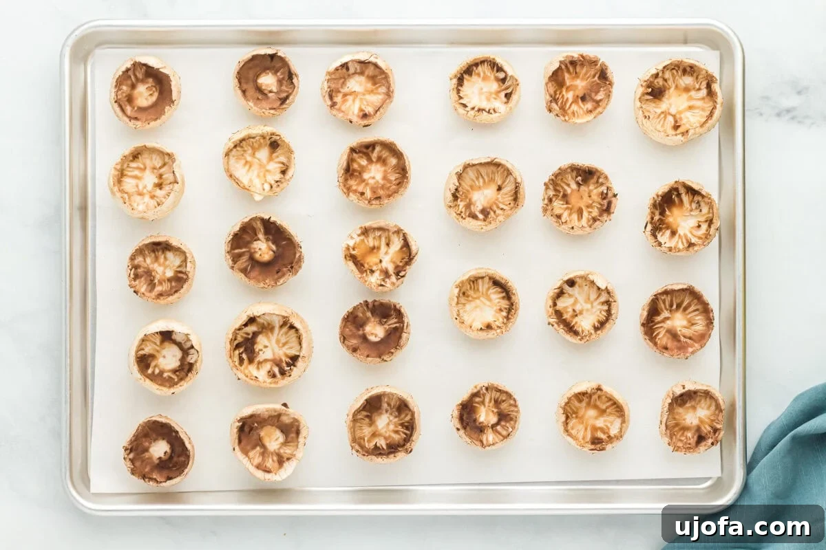 Wholesome Mushroom Poppers 8 Mushroom caps on a parchment lined baking sheet.