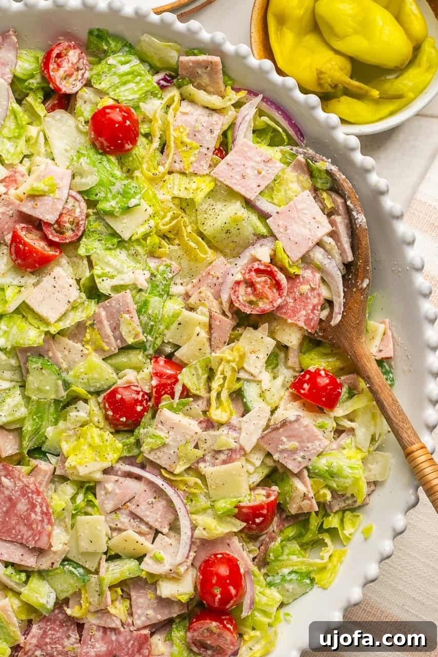 a grinder salad in a white bowl with a wooden spoon
