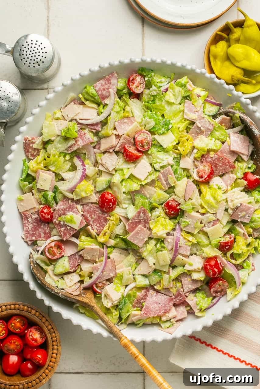 an overhead shot of a white salad bowl filled with grinder salad ingredients tossed in dressing